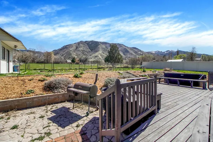 Deck featuring a fenced backyard, a patio, a mountain view, and area for grilling
