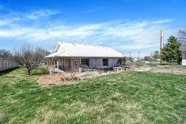 Back of house with a hot tub, a patio, and a metal roof