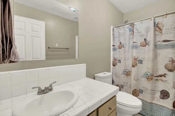 Full bath with a shower with curtain, vanity, and decorative backsplash