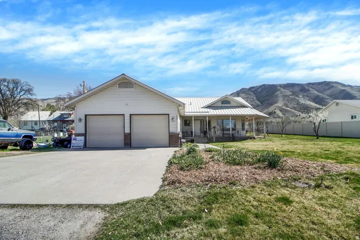 Single story home featuring a porch, driveway, a garage, a standing seam roof, and a mountain view