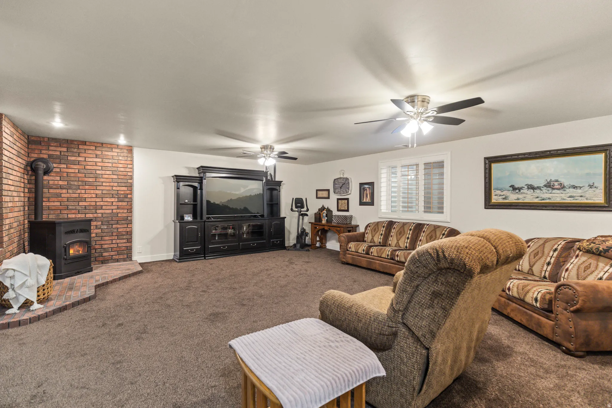 Living room with carpet, a wood stove, and ceiling fan