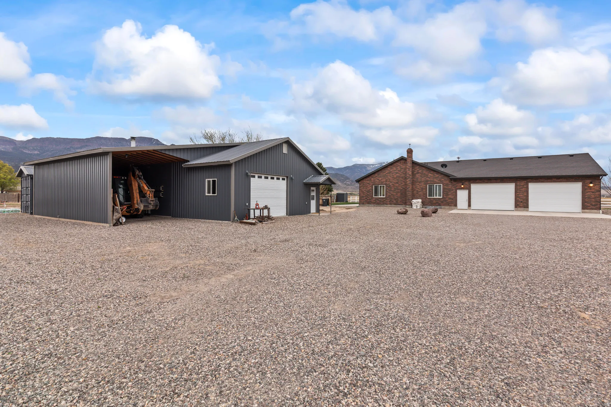 View of front of property with a mountain view, an outbuilding, a garage, driveway, and a carport