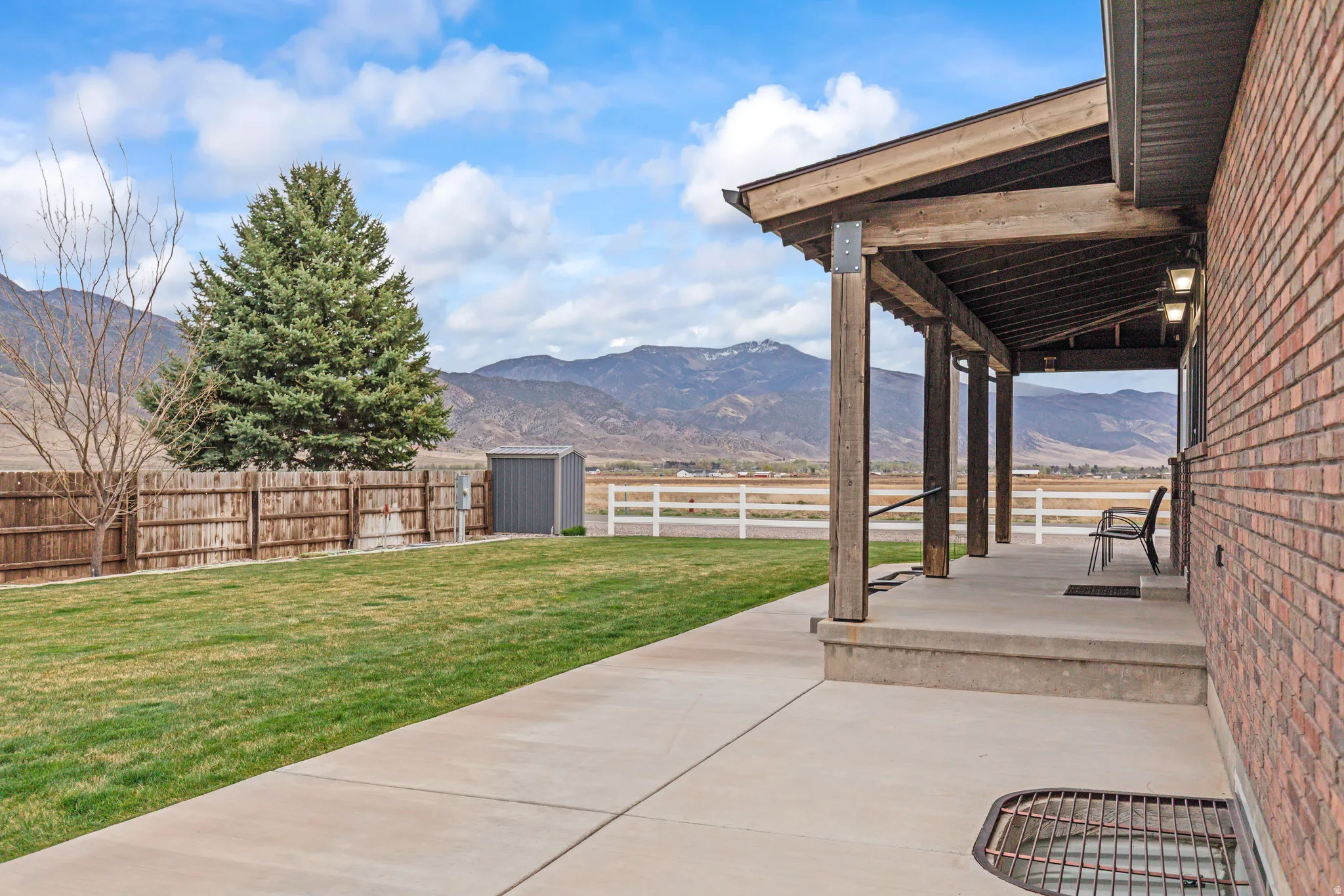 Fenced backyard with a patio area, a mountain view, and a storage unit