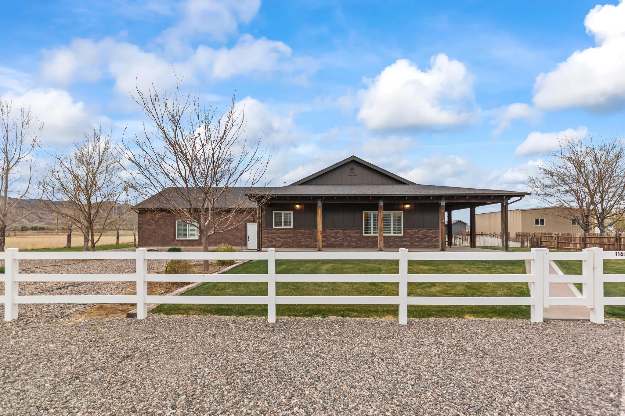 Ranch-style home with a fenced front yard, board and batten siding, brick siding, and covered porch