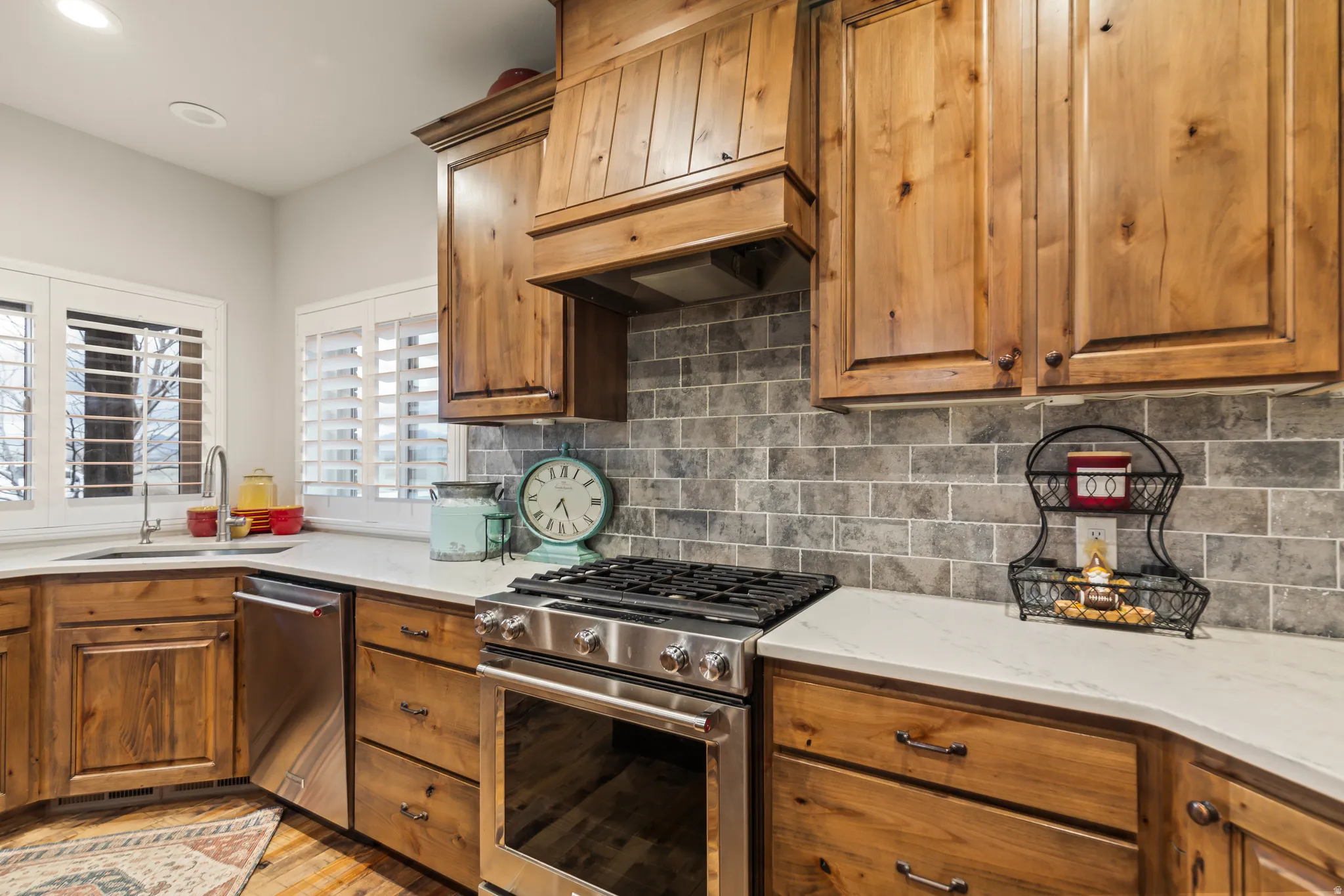 Kitchen featuring stainless steel appliances, light stone counters, wood finish cabinetry, decorative backsplash, and recessed lighting