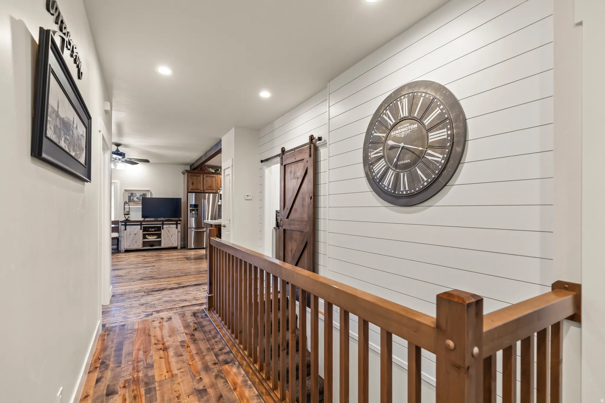 Hallway with a barn door, recessed lighting, dark wood-type flooring, and wood walls