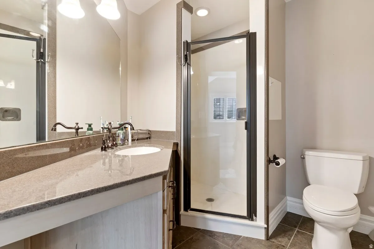 Full bathroom with a shower stall, vanity, dark tile patterned flooring, and recessed lighting