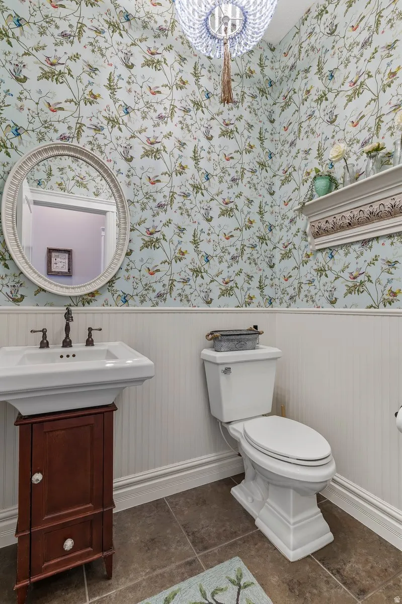 Half bath with wainscoting, vanity, and wallpapered walls