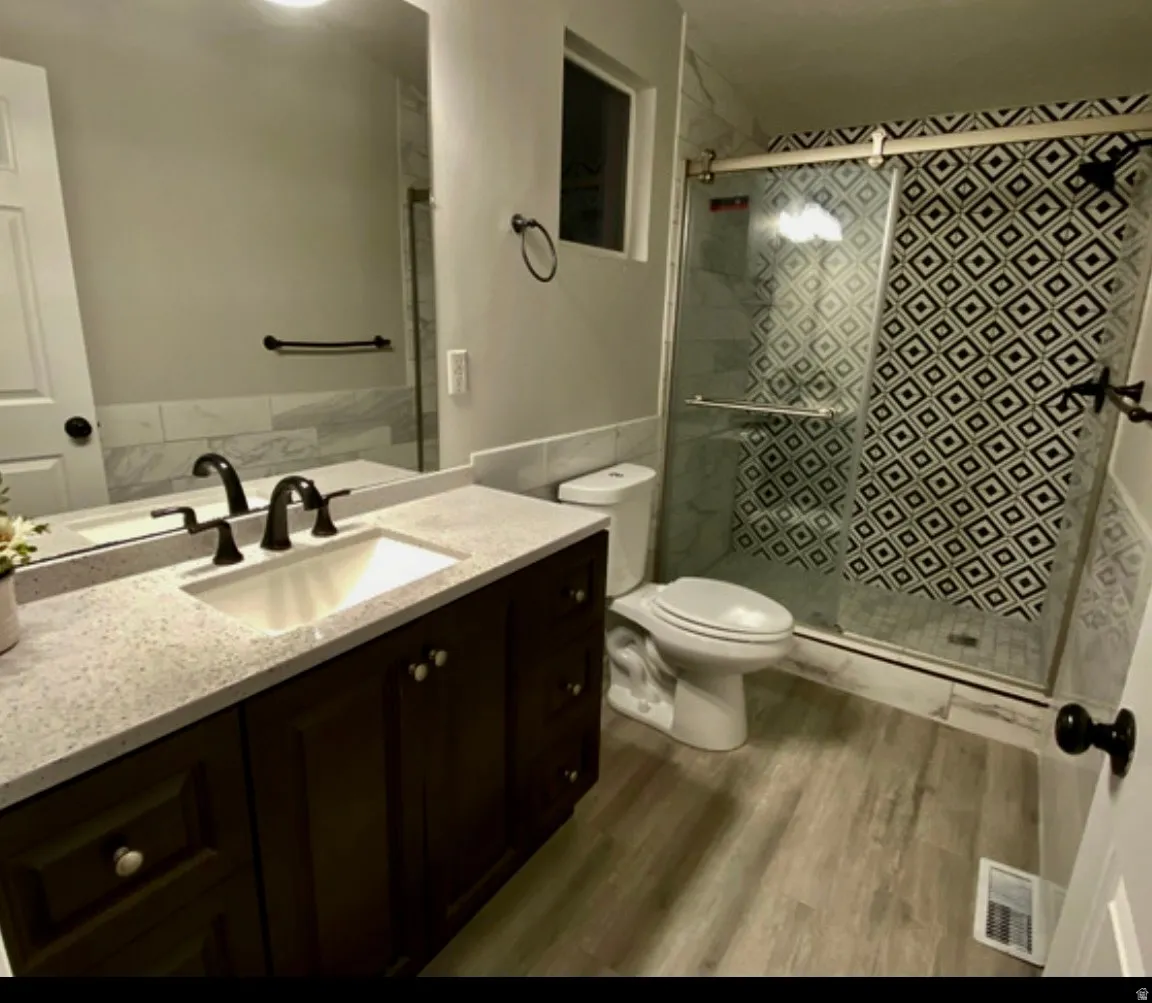 Full bath with vanity, a shower stall, and dark wood-style floors
