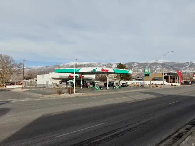View of asphalt street featuring a mountain view, street lighting, curbs, and sidewalks