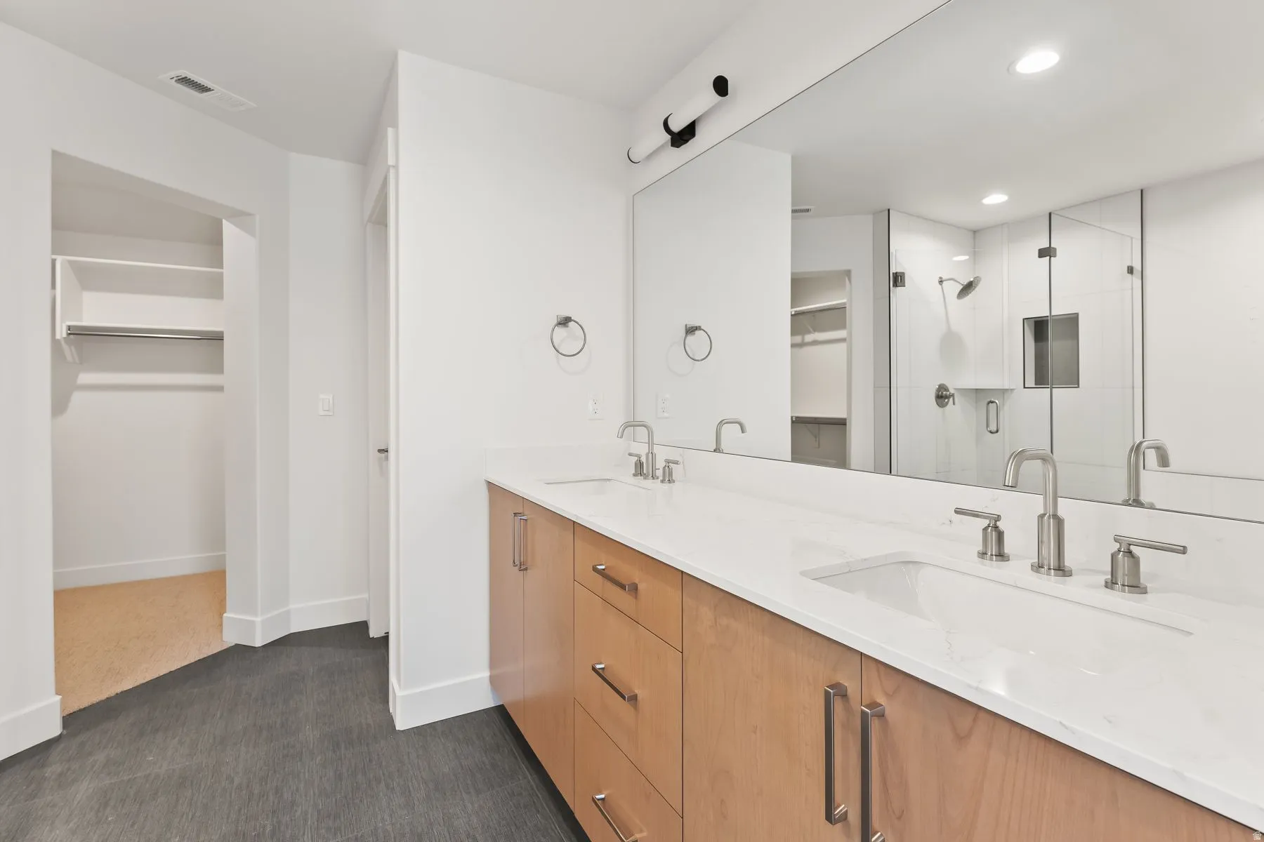 Bathroom featuring a spacious closet, double vanity, a shower stall, dark carpet, and recessed lighting