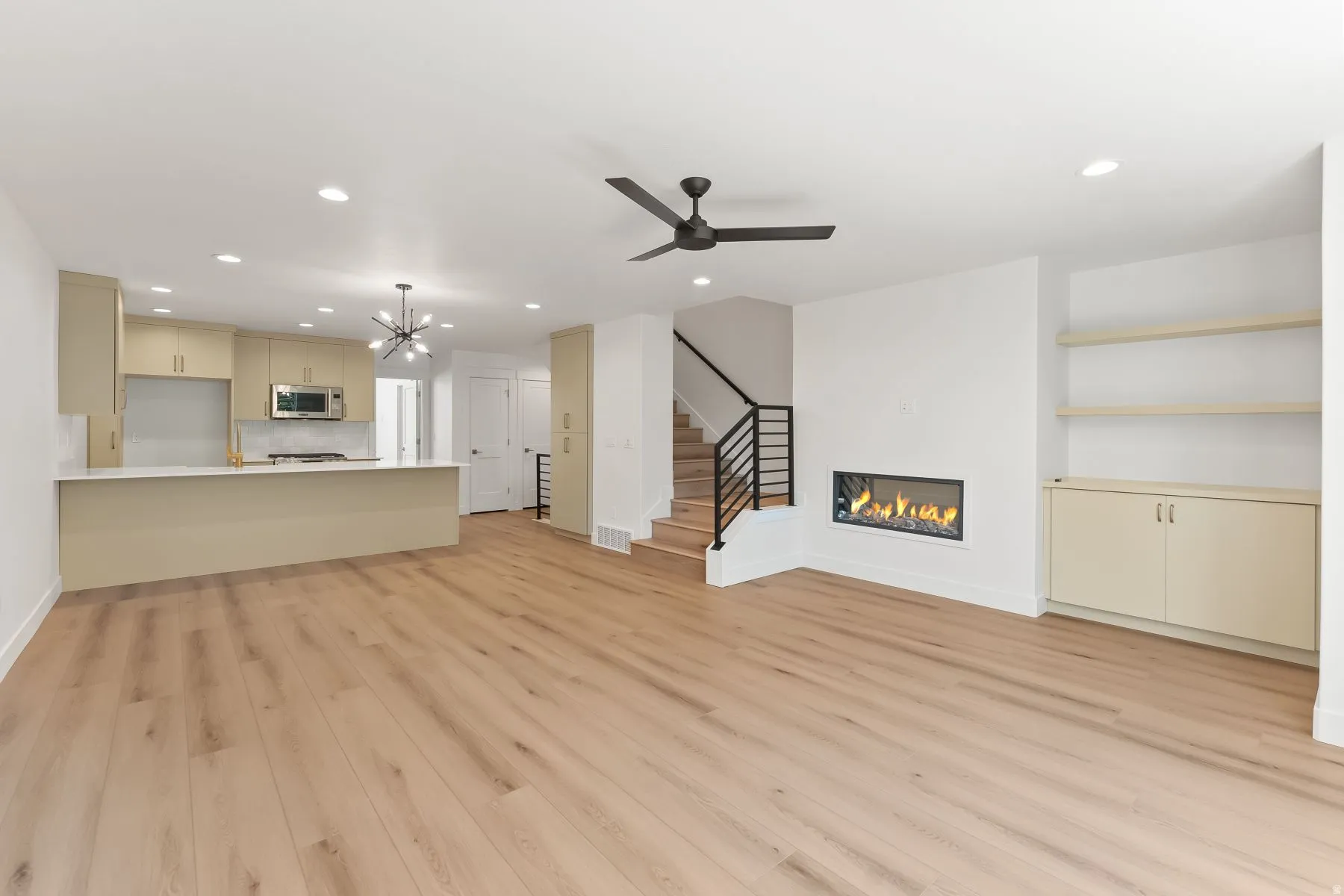 Unfurnished living room with a chandelier, light wood-style floors, a glass covered fireplace, and a ceiling fan