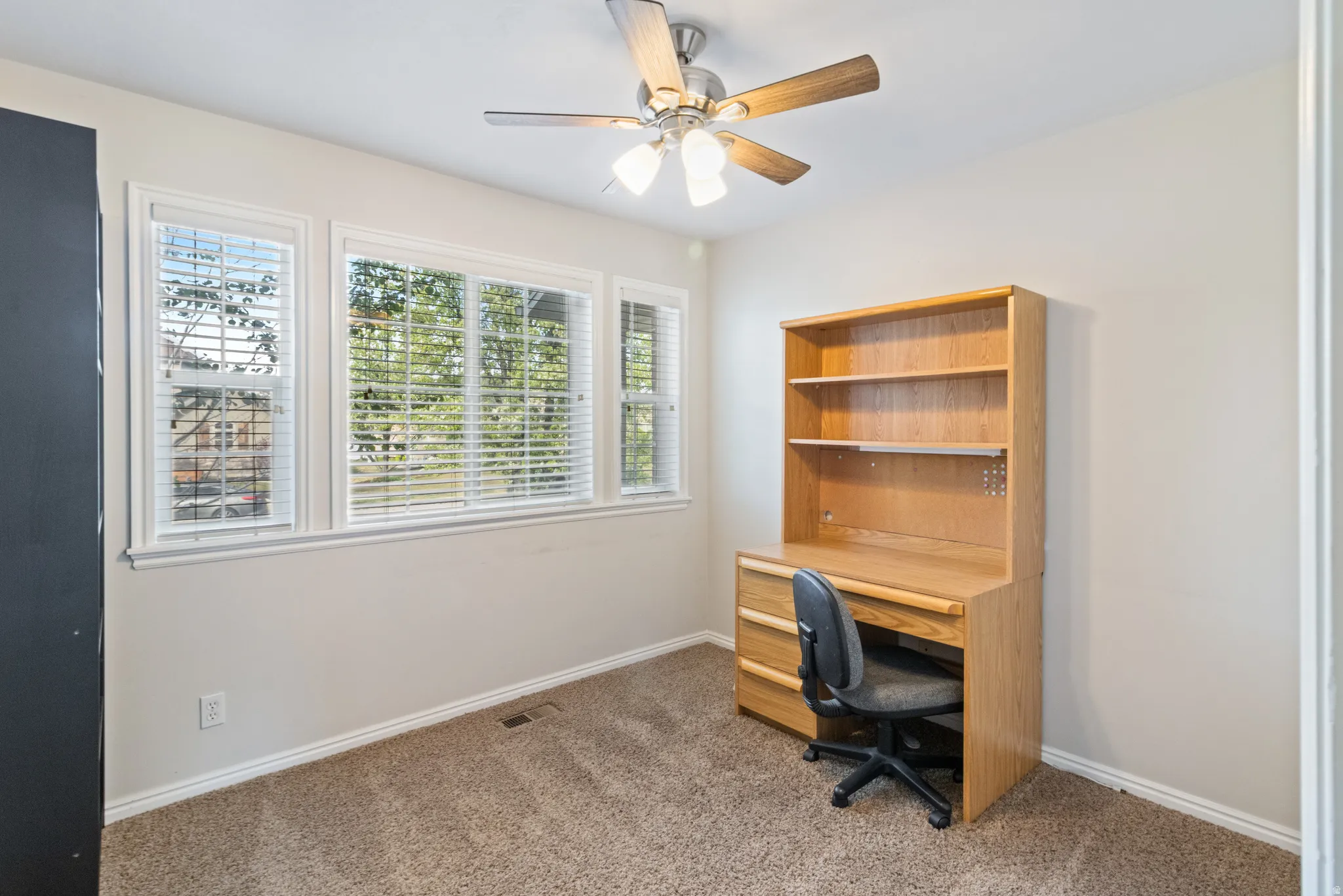 Home office featuring dark carpet and a ceiling fan