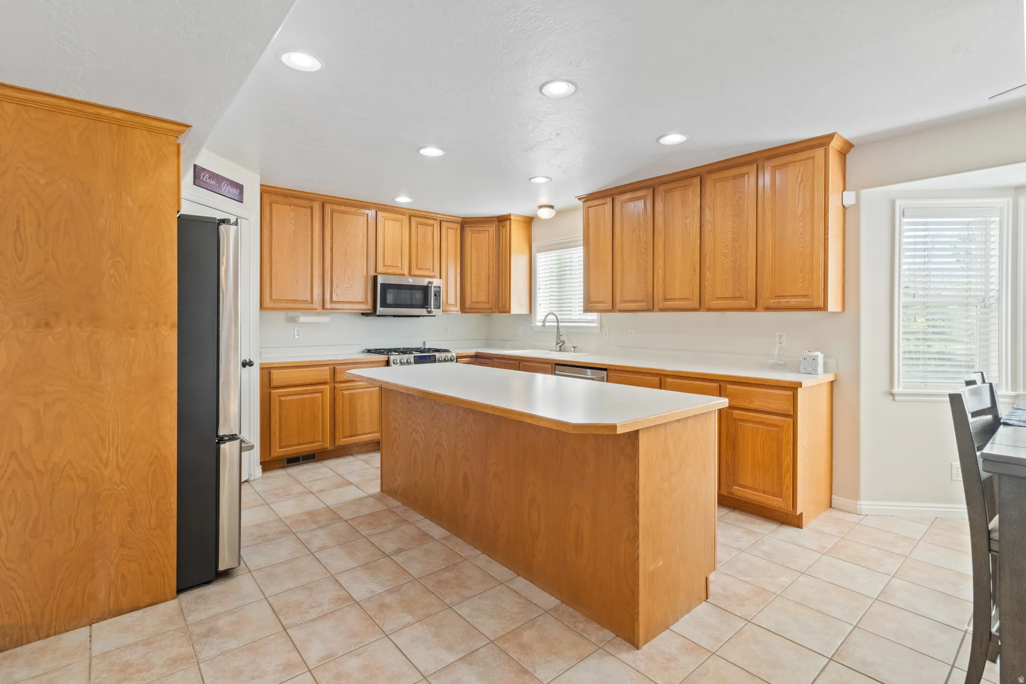 Kitchen featuring light countertops, light tile patterned flooring, stainless steel appliances, recessed lighting, and a center island