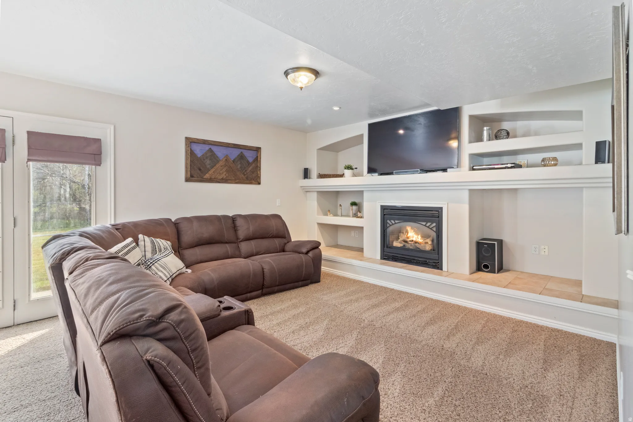 Carpeted living area featuring built in shelves and a glass covered fireplace