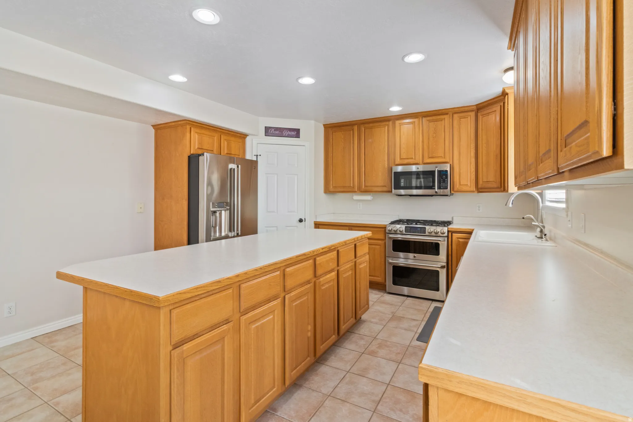 Kitchen with light countertops, stainless steel appliances, recessed lighting, a center island, and light tile patterned floors
