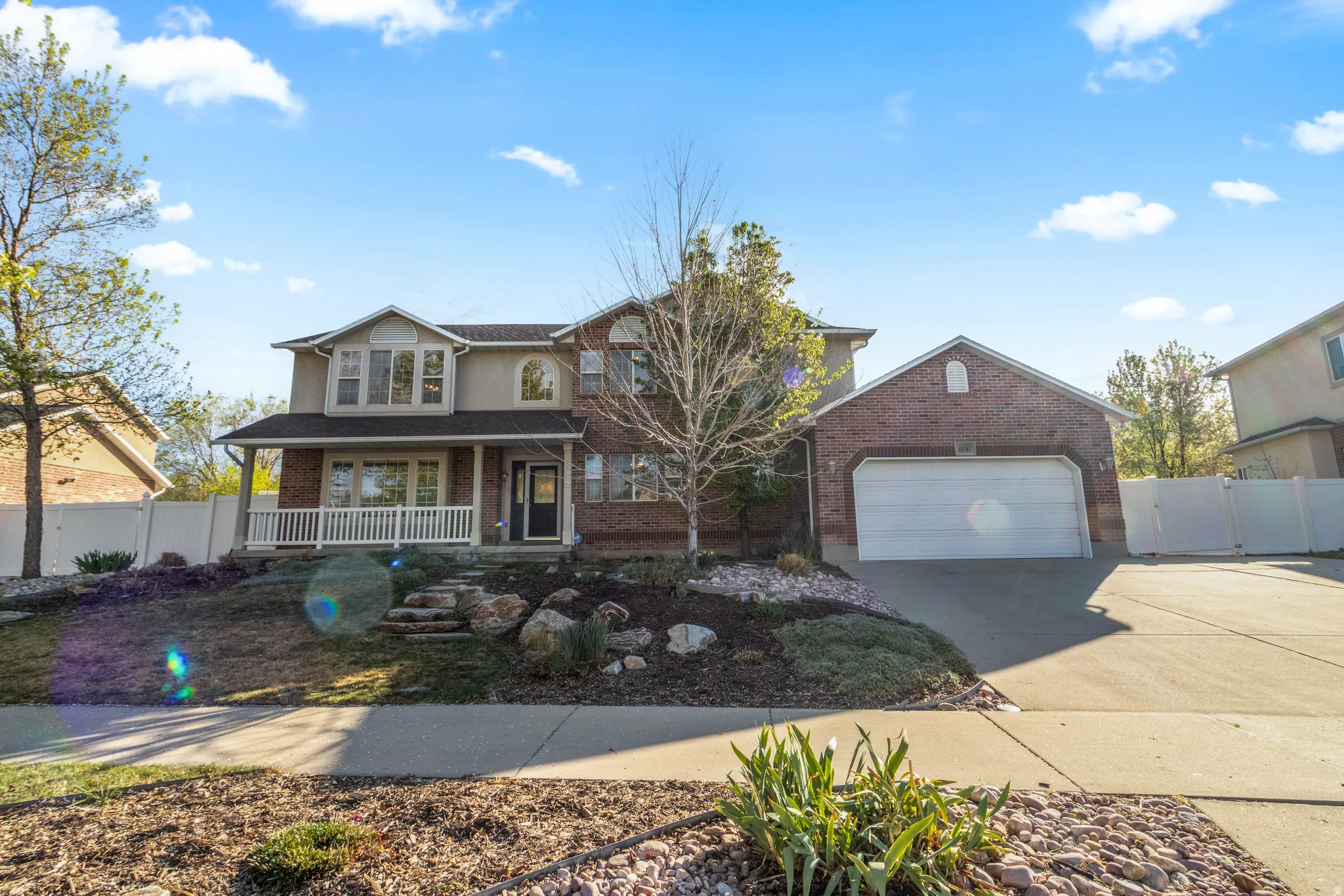 Traditional home with a porch, driveway, an attached garage, a gate, and brick siding