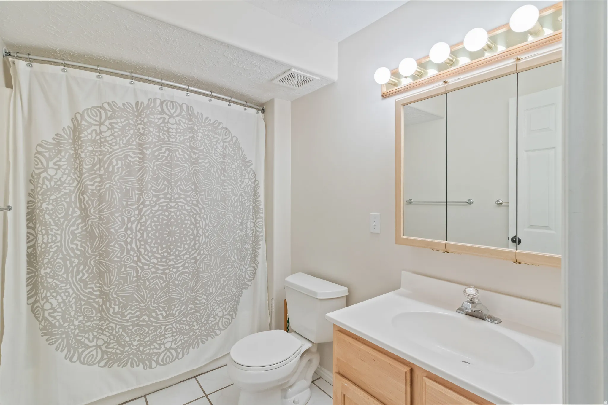 Full bathroom with vanity, light tile patterned floors, and shower / tub combo with curtain