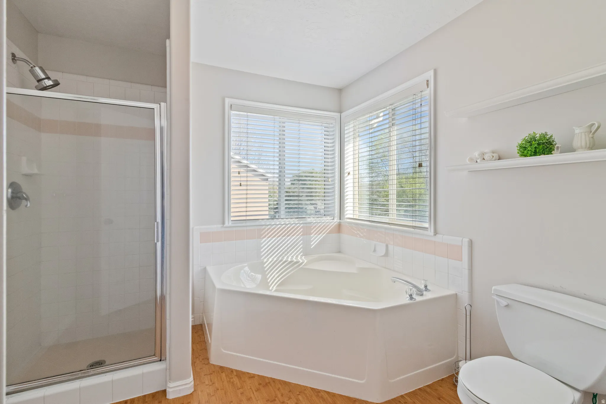 Bathroom with a garden tub, a shower stall, and light wood-style floors