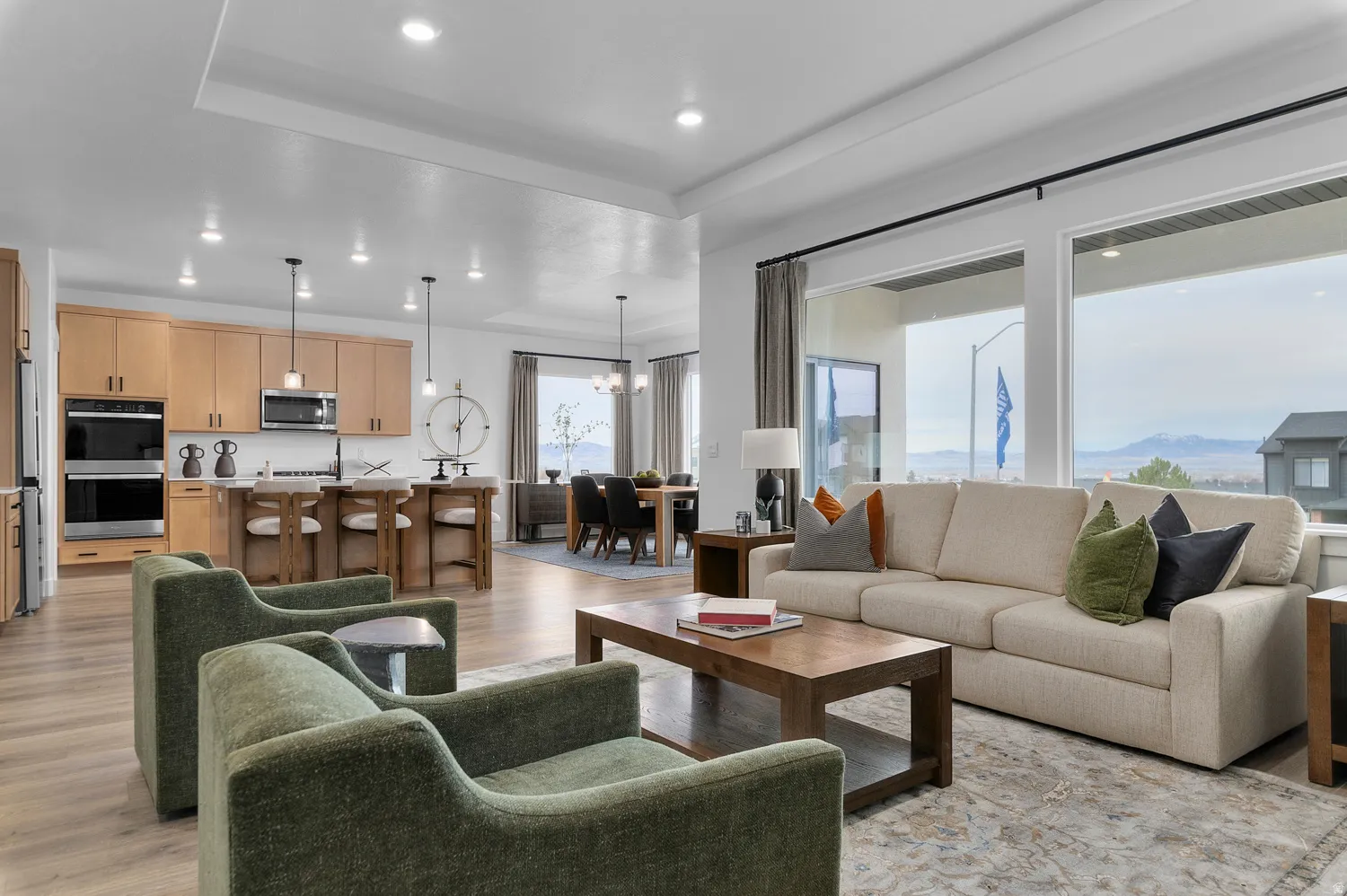 Living room featuring light wood-style flooring, suspended lighting, a raised ceiling, and a mountain view