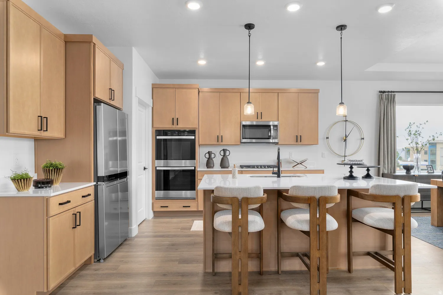 Kitchen featuring light wood finish cabinets, stainless steel appliances, light stone counters, and light wood finished floors