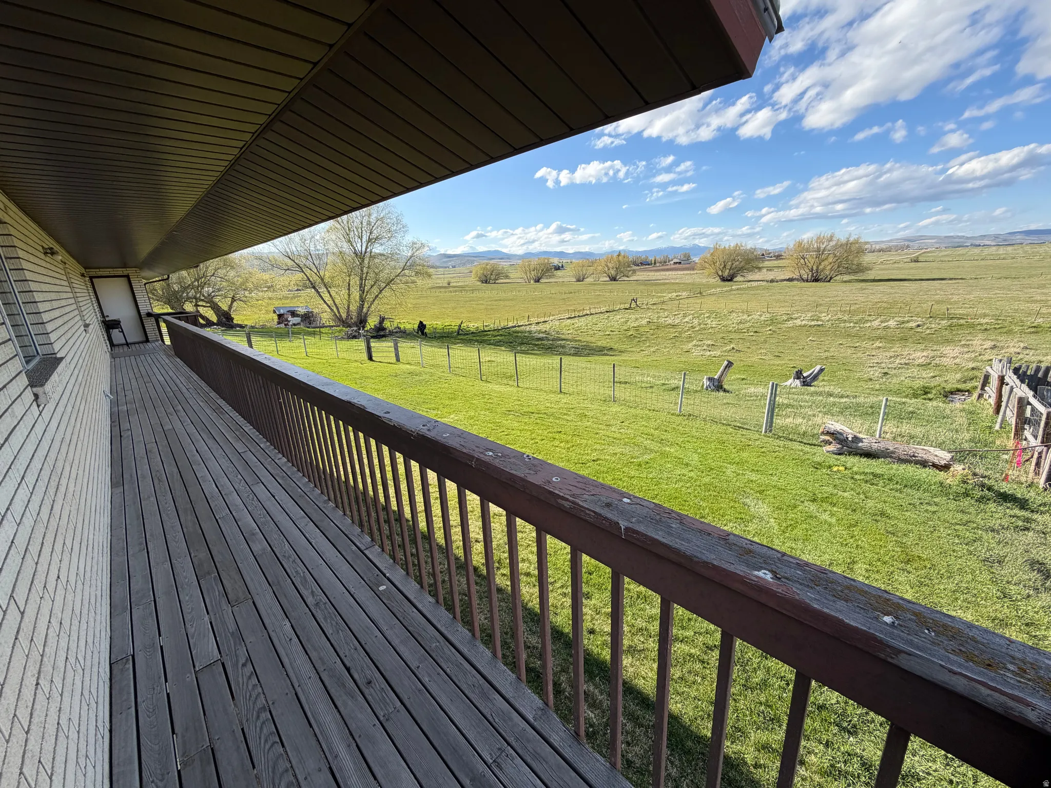 Wooden deck featuring a view of countryside and a fenced backyard