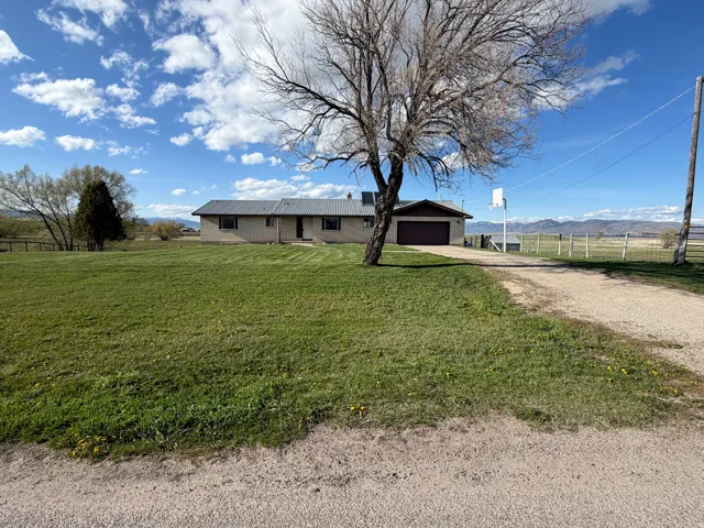 View of front facade with driveway, a view of rural / pastoral area, and an attached garage