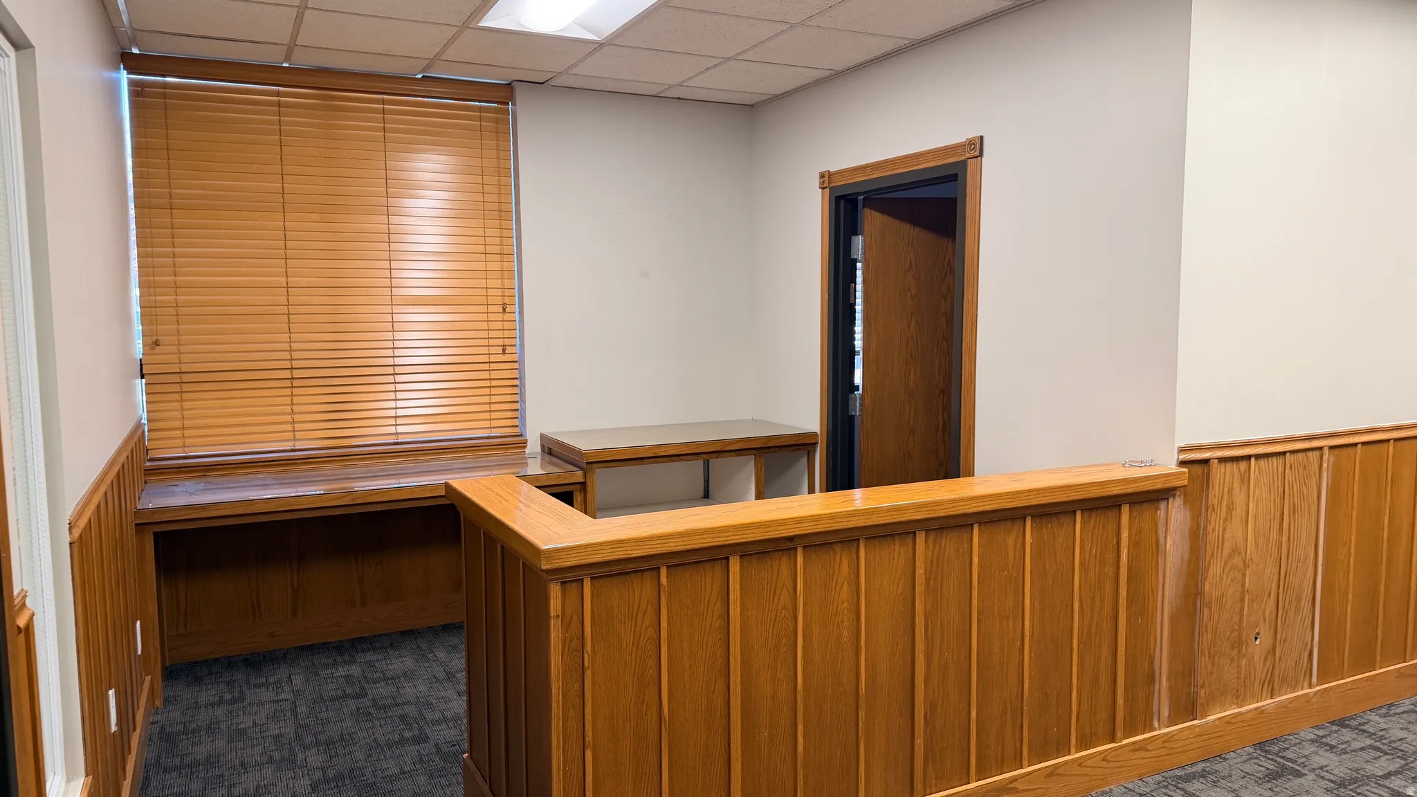 Reception area featuring wood paneling, a built-in desk, wood-finish blinds, an interior doorway, and recessed ceiling lighting