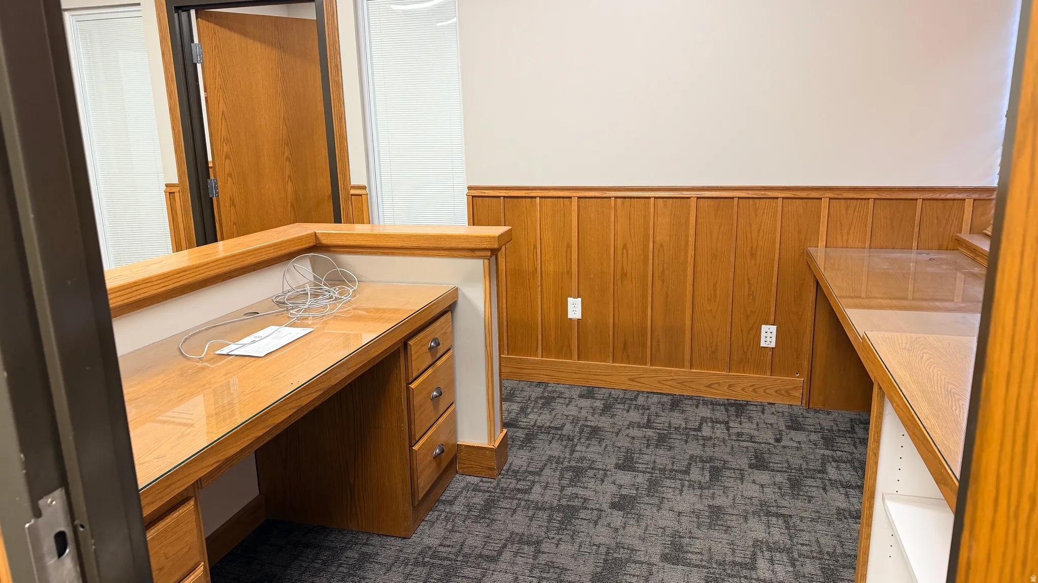 Built-in wood-finish reception desk with glass top, integrated drawer storage, and a half-wall partition