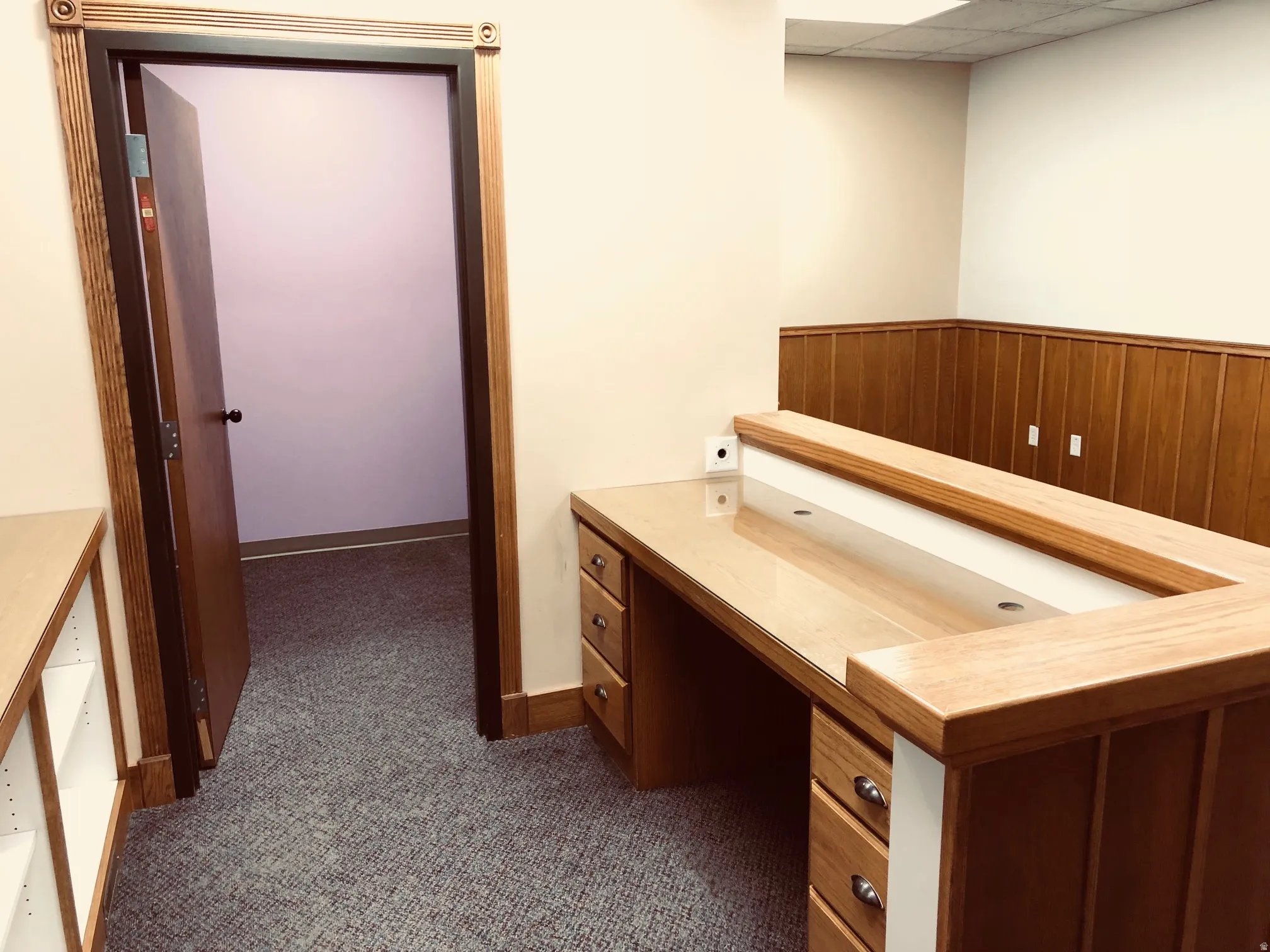 Office area featuring built in desk, a paneled ceiling, and dark carpet