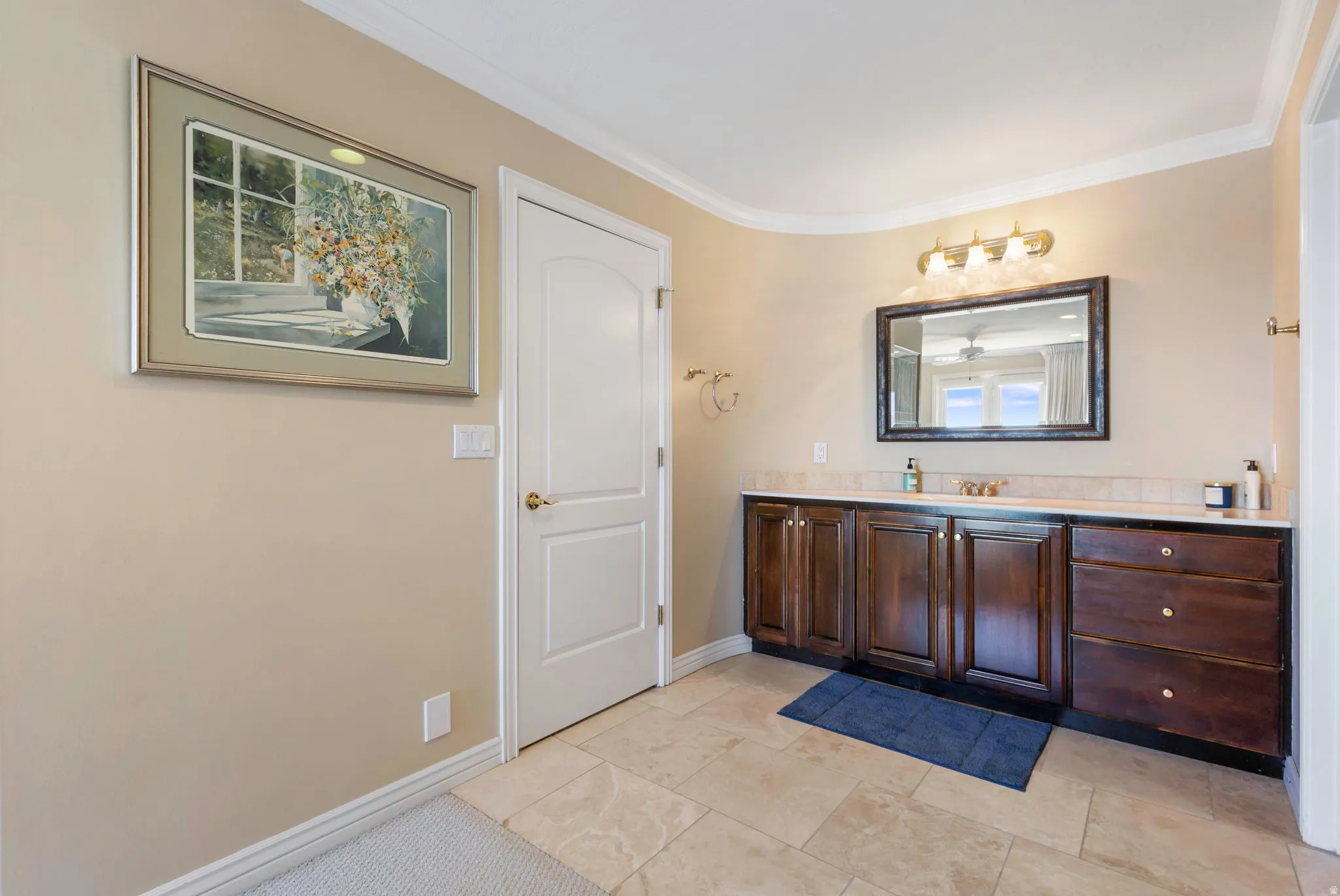 Bathroom with vanity, crown molding, and light tile patterned floors