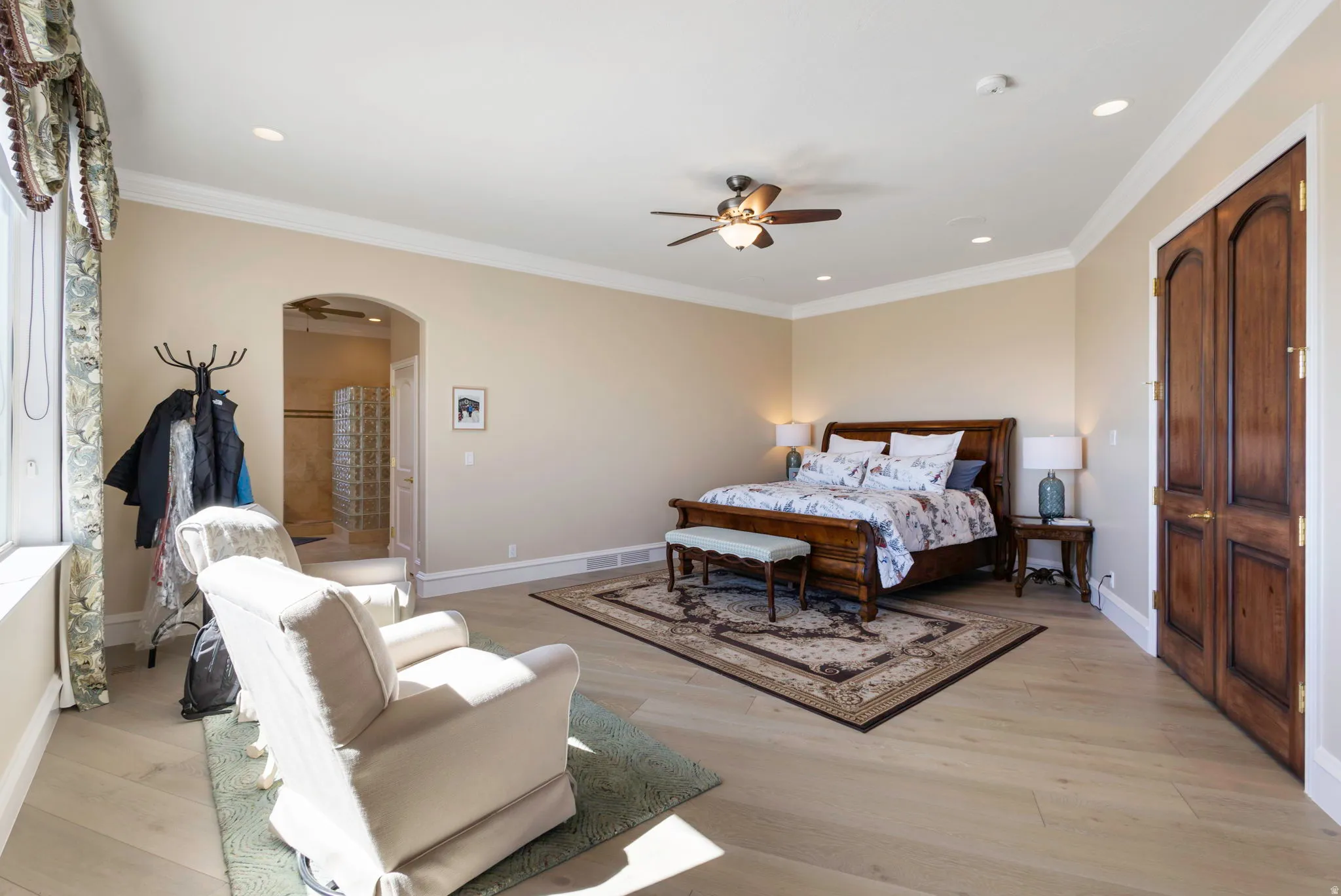 Bedroom with ornamental molding, arched walkways, light wood-style flooring, a ceiling fan, and recessed lighting