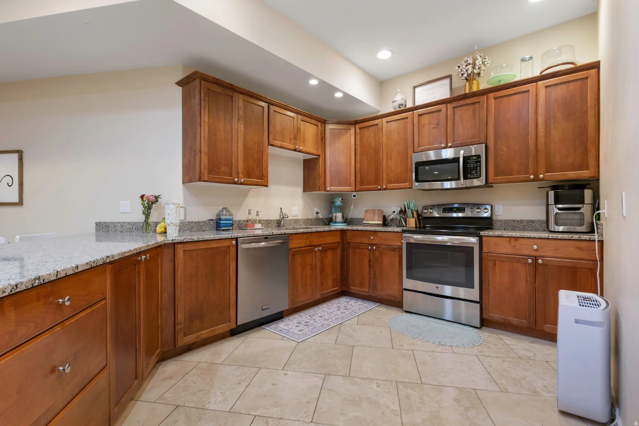 Kitchen featuring stainless steel appliances, wood finish cabinets, light stone counters, and recessed lighting