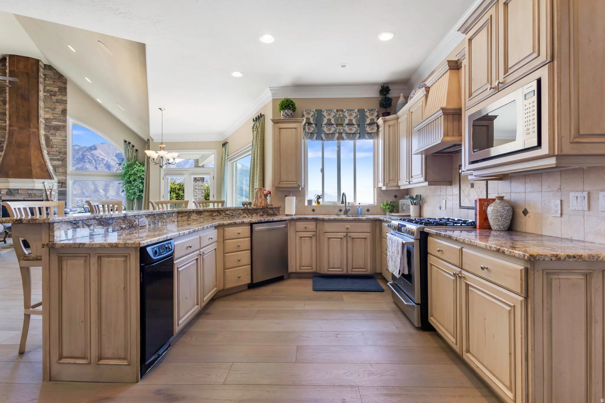 Kitchen featuring a breakfast bar area, stainless steel appliances, light stone countertops, a peninsula, and backsplash