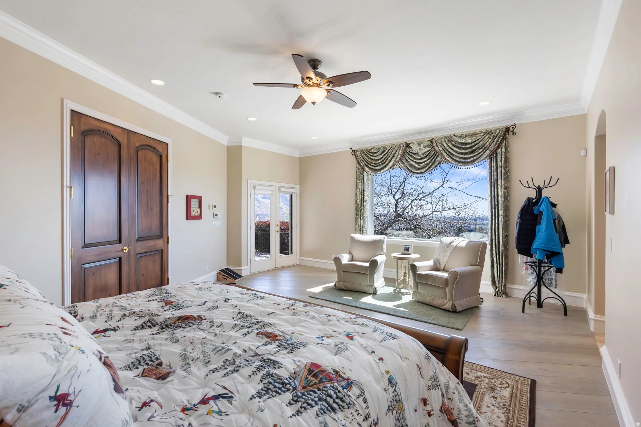 Bedroom featuring access to exterior, light wood-type flooring, ornamental molding, ceiling fan, and arched walkways