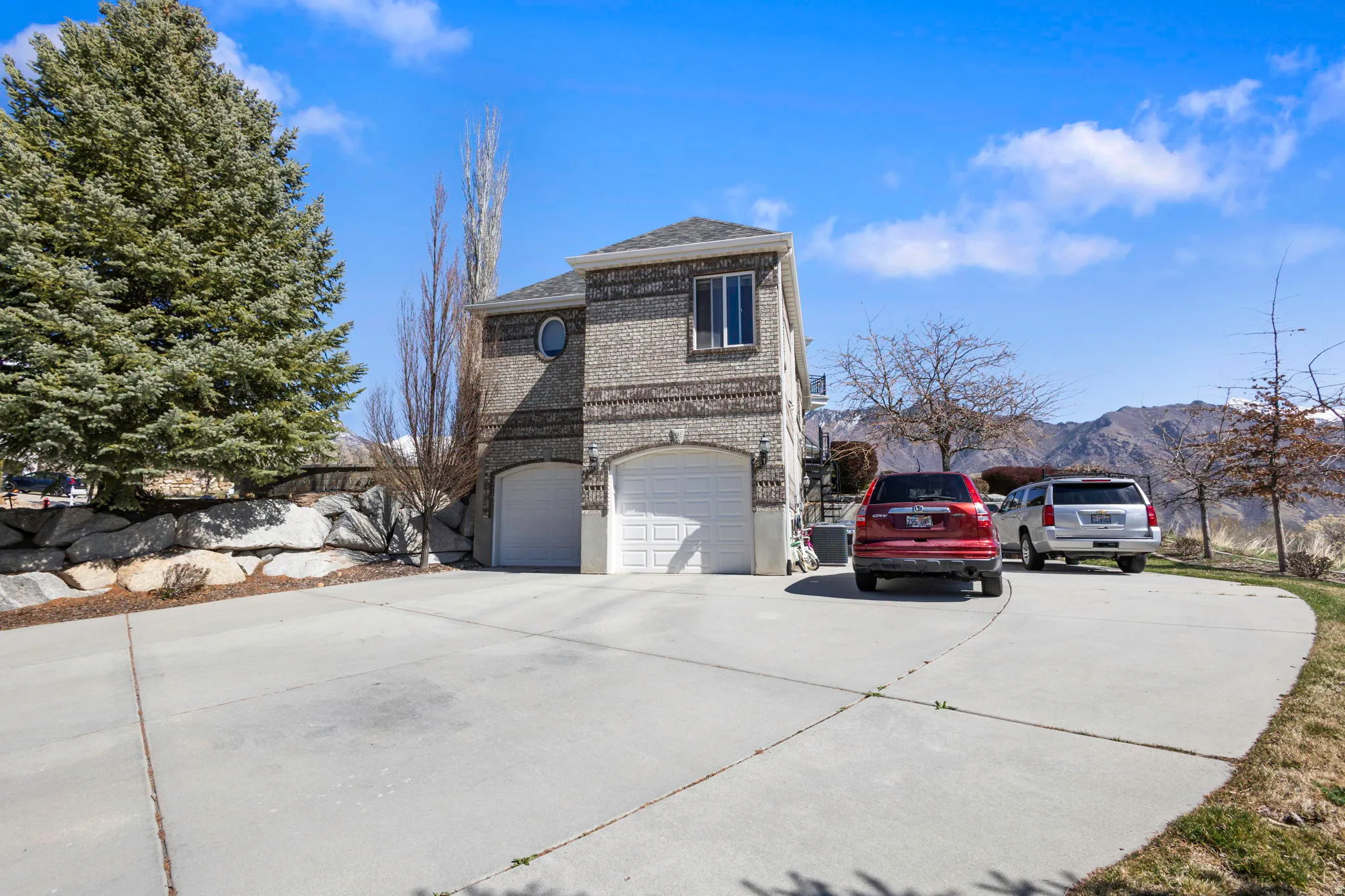 View of side of property with concrete driveway, brick siding, an attached garage, and a mountain view