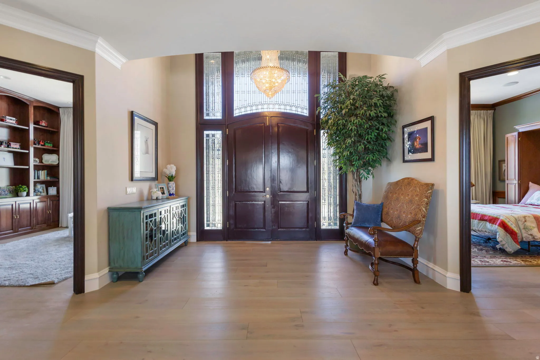 Entryway featuring crown molding, light wood-style floors, and hanging lights
