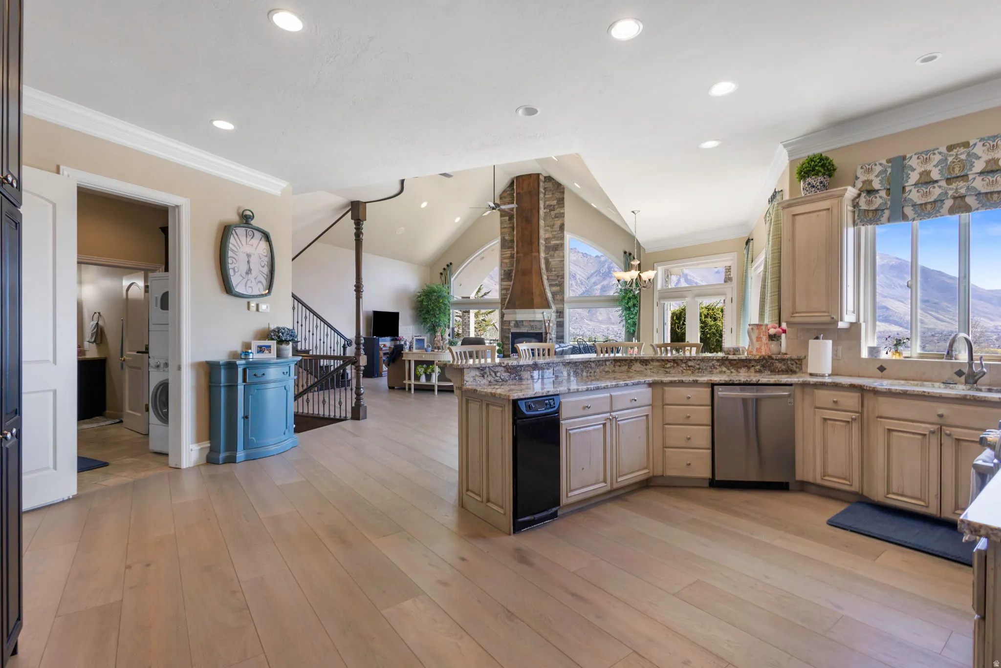 Kitchen featuring a peninsula, ceiling fan, vaulted ceiling, ornamental molding, and light stone countertops