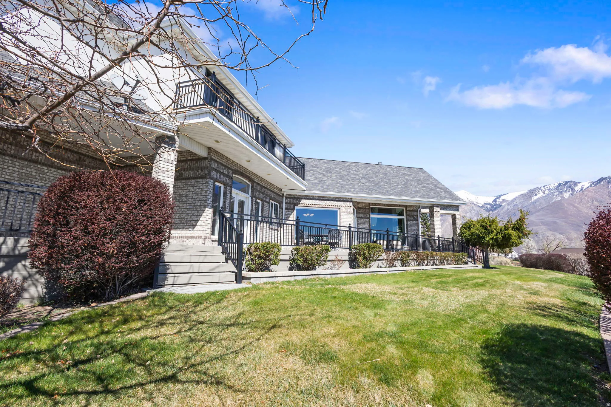 Rear view of house with brick siding, a lawn, and a mountain view