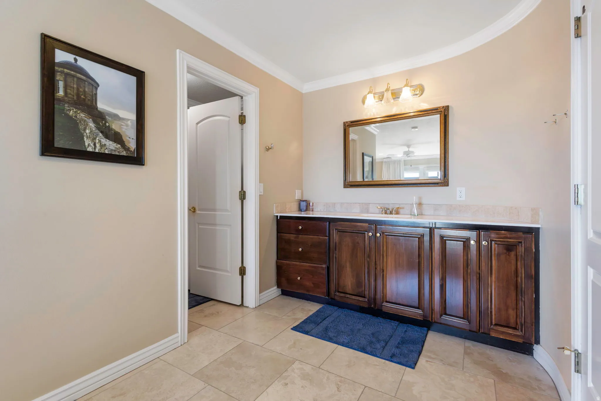 Bathroom with vanity, ornamental molding, and light tile patterned flooring