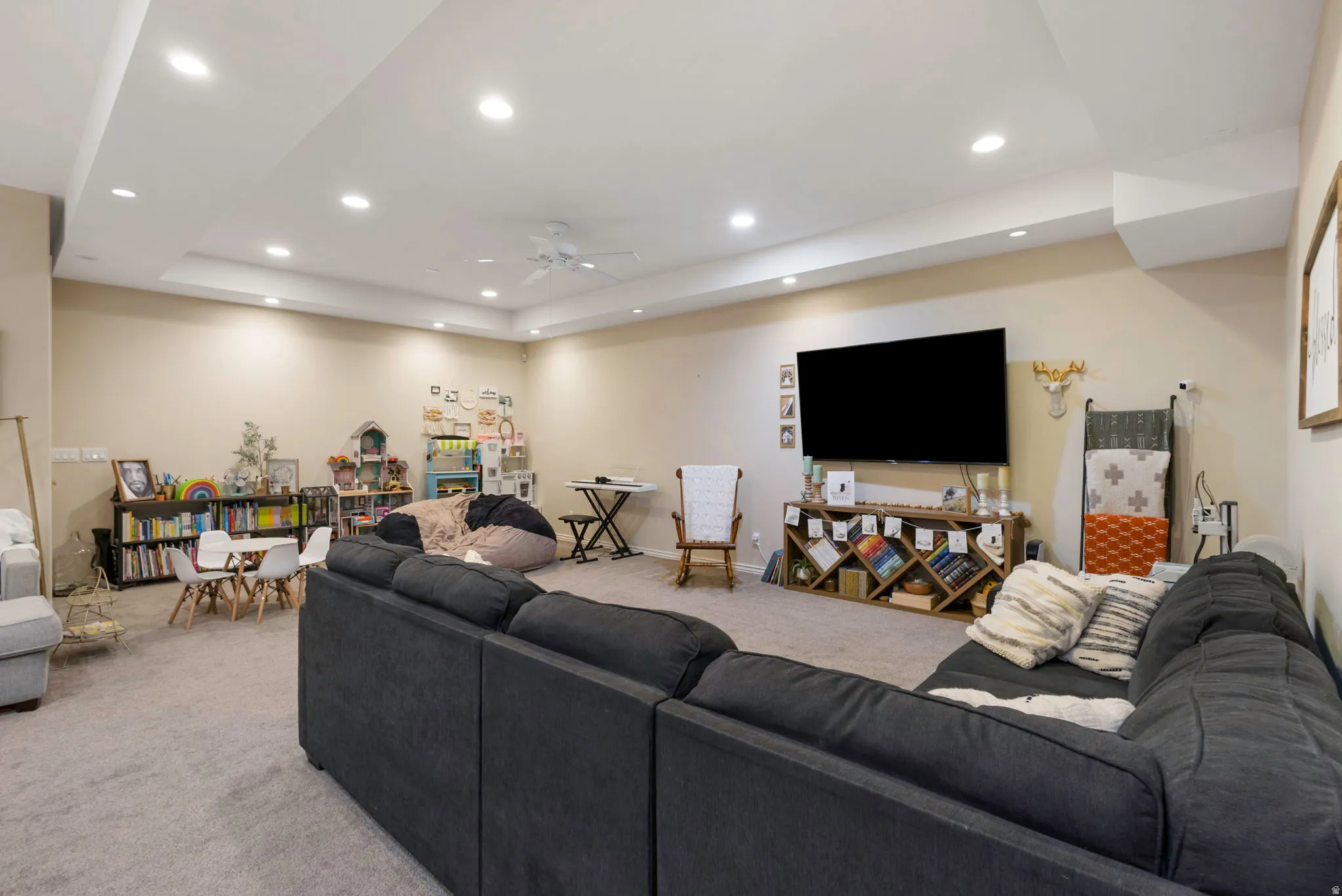 Living room with light carpet, a ceiling fan, recessed lighting, and a raised ceiling