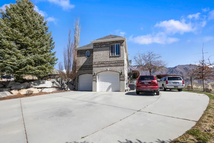 View of side of property with concrete driveway, brick siding, an attached garage, and a mountain view