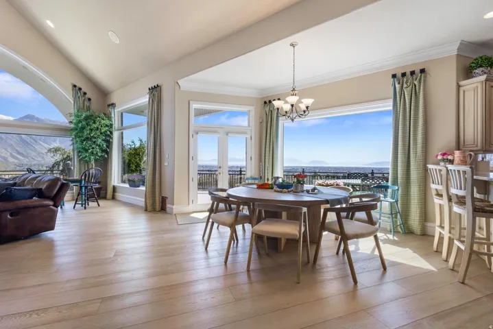 Dining area featuring healthy amount of natural light, light wood-style floors, suspended lighting, crown molding, and a mountain view