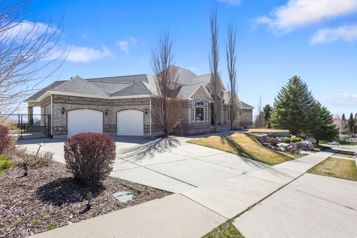 View of front of house with concrete driveway, a garage, a shingled roof, brick siding, and a gate