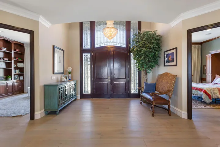 Entryway featuring crown molding, light wood-style floors, and hanging lights