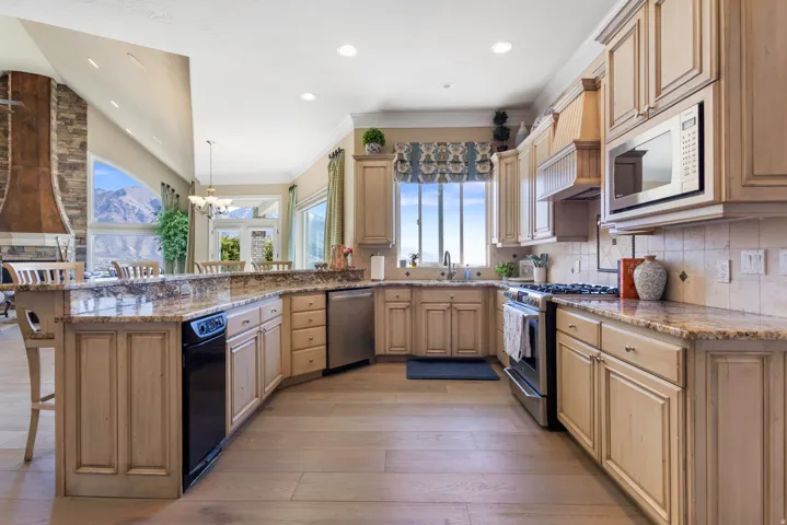 Kitchen featuring a breakfast bar area, stainless steel appliances, light stone countertops, a peninsula, and backsplash