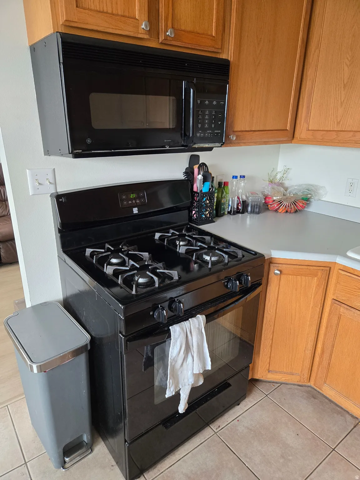 Kitchen with black appliances, light countertops, wood finish cabinets, and light tile patterned floors