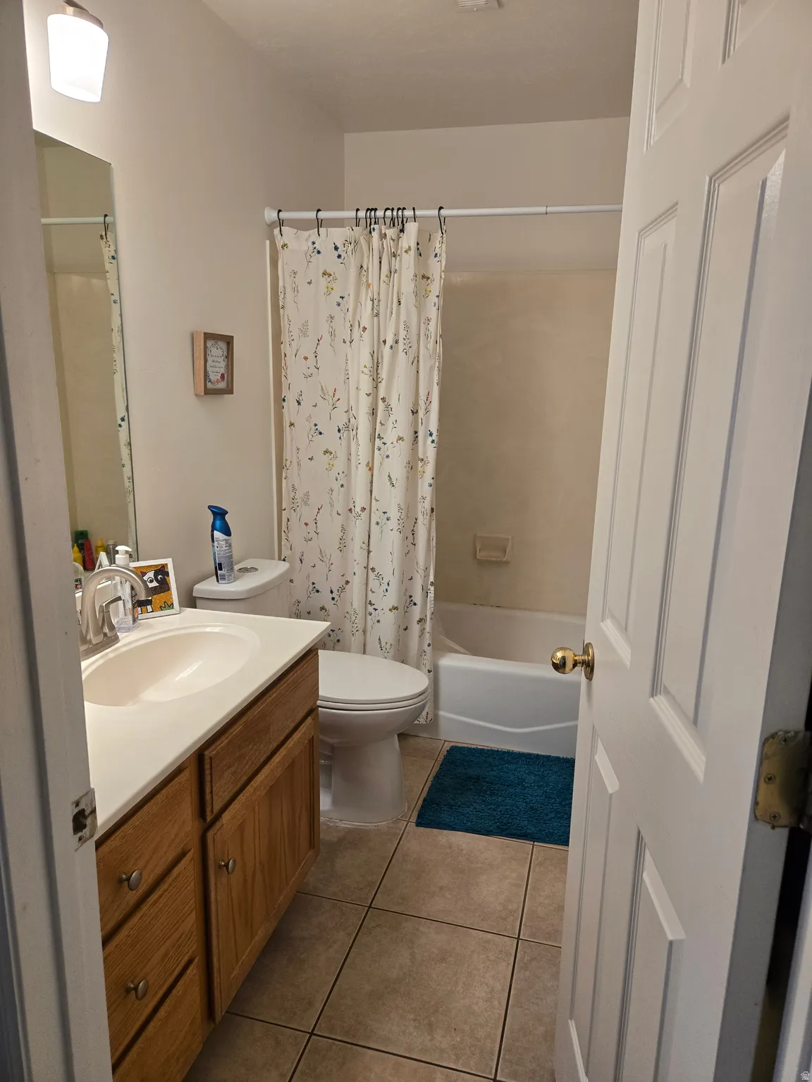 Bathroom featuring vanity, shower / bath combo with shower curtain, and light tile patterned floors