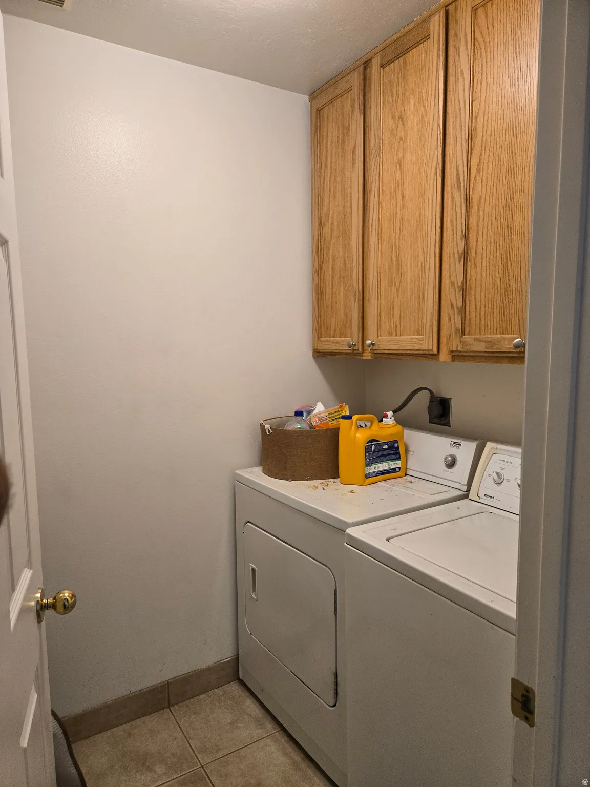 Laundry area featuring cabinet space, separate washer and dryer, and light tile patterned floors