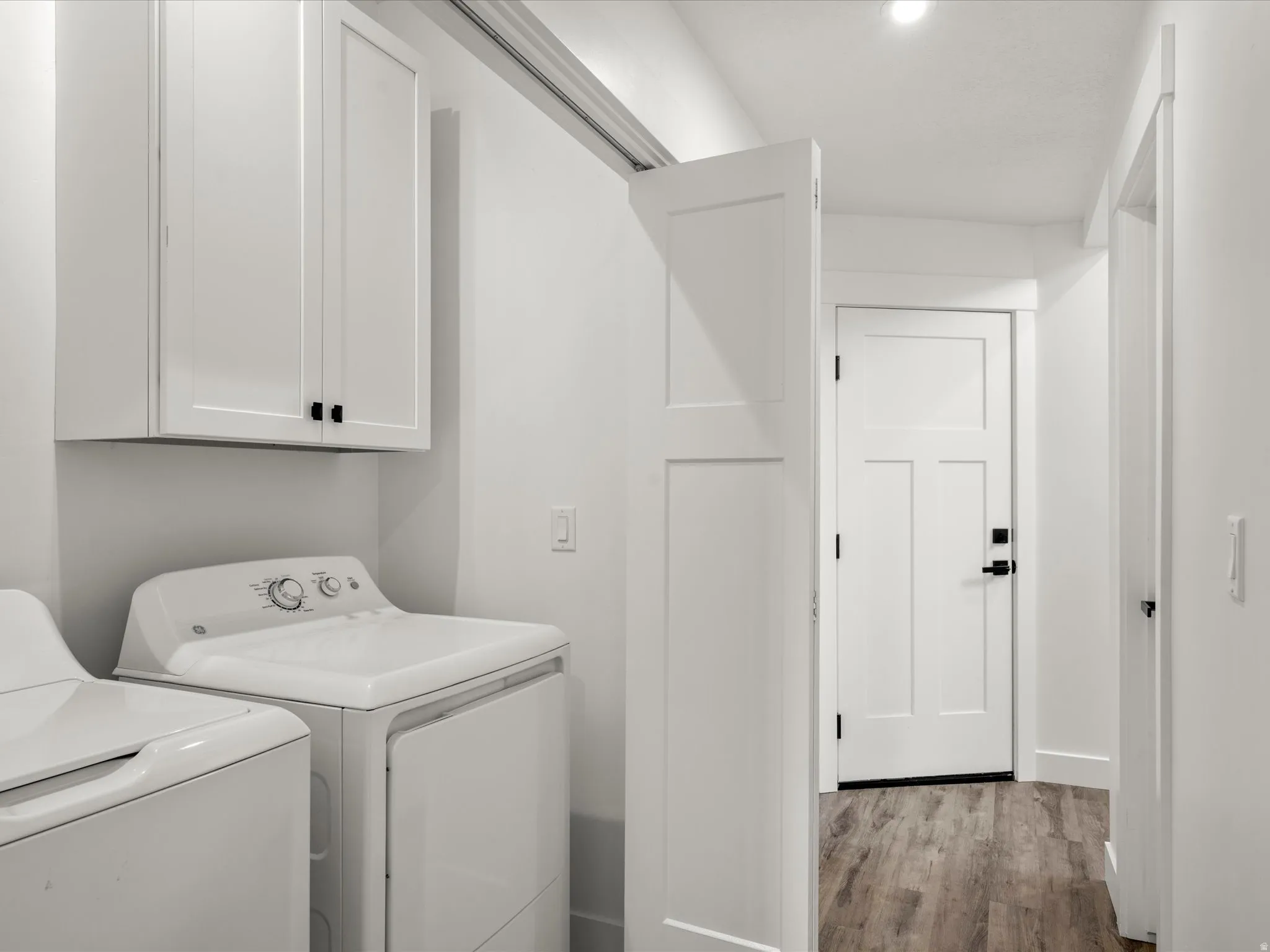 Laundry area featuring light wood-type flooring, separate washer and dryer, and cabinet space
